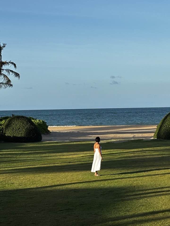 Linda in a white dress, standing on green grass and looking out at the ocean on Florida's Treasure Coast
